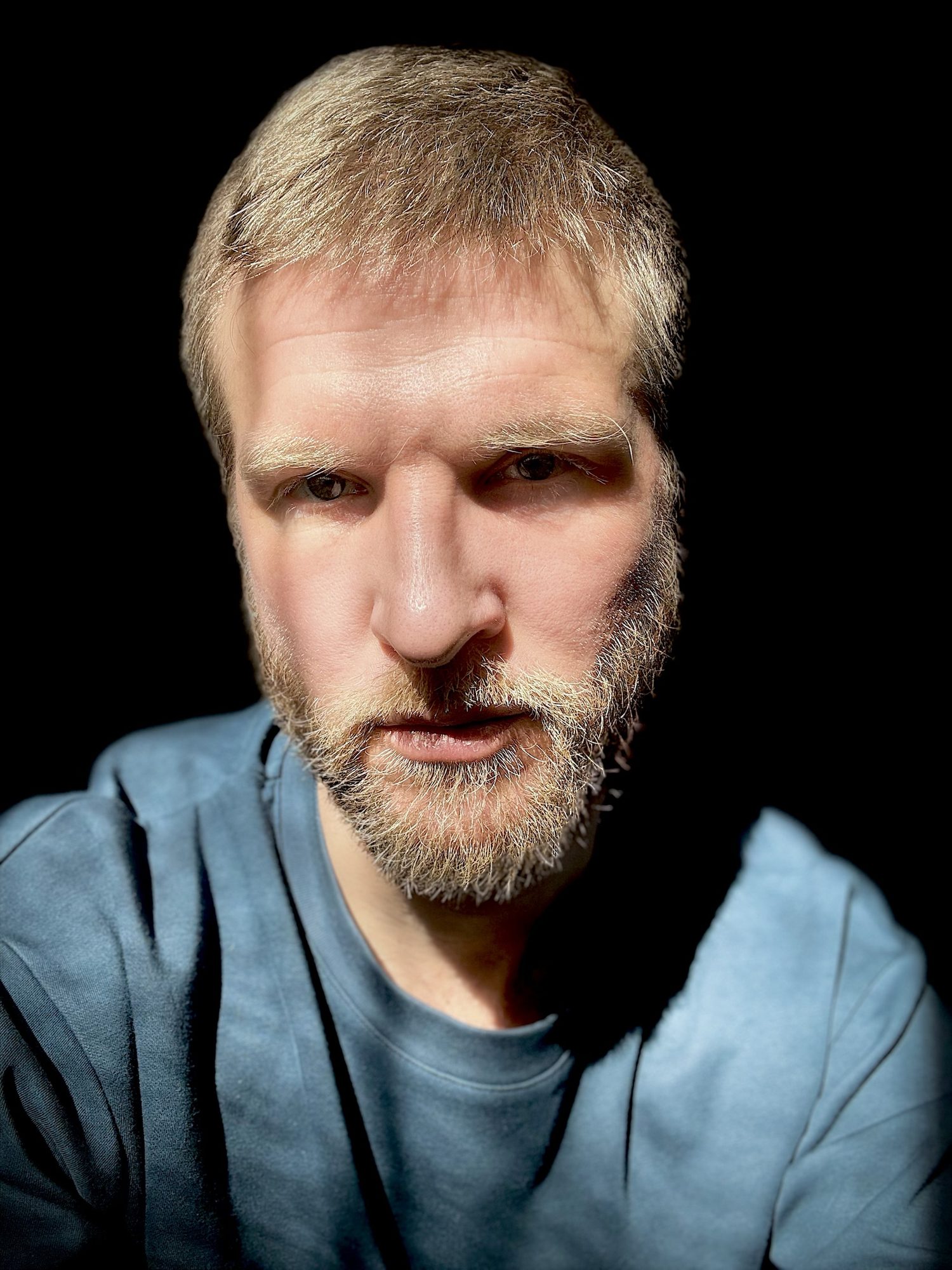 Portrait barbu sur fond noir, chemise bleue