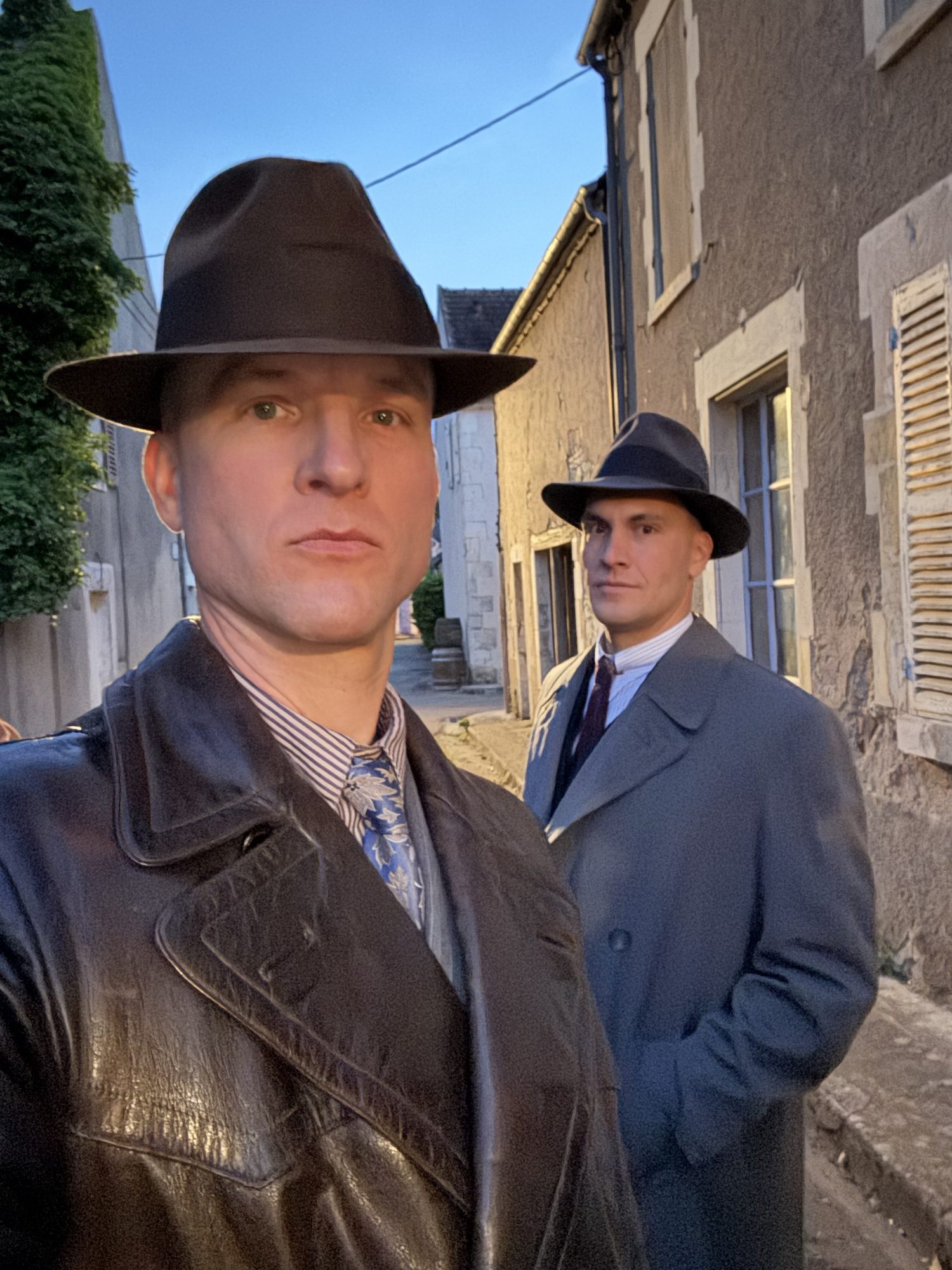 En manteau de cuir et chapeau, dans une ruelle, avec un second comédien