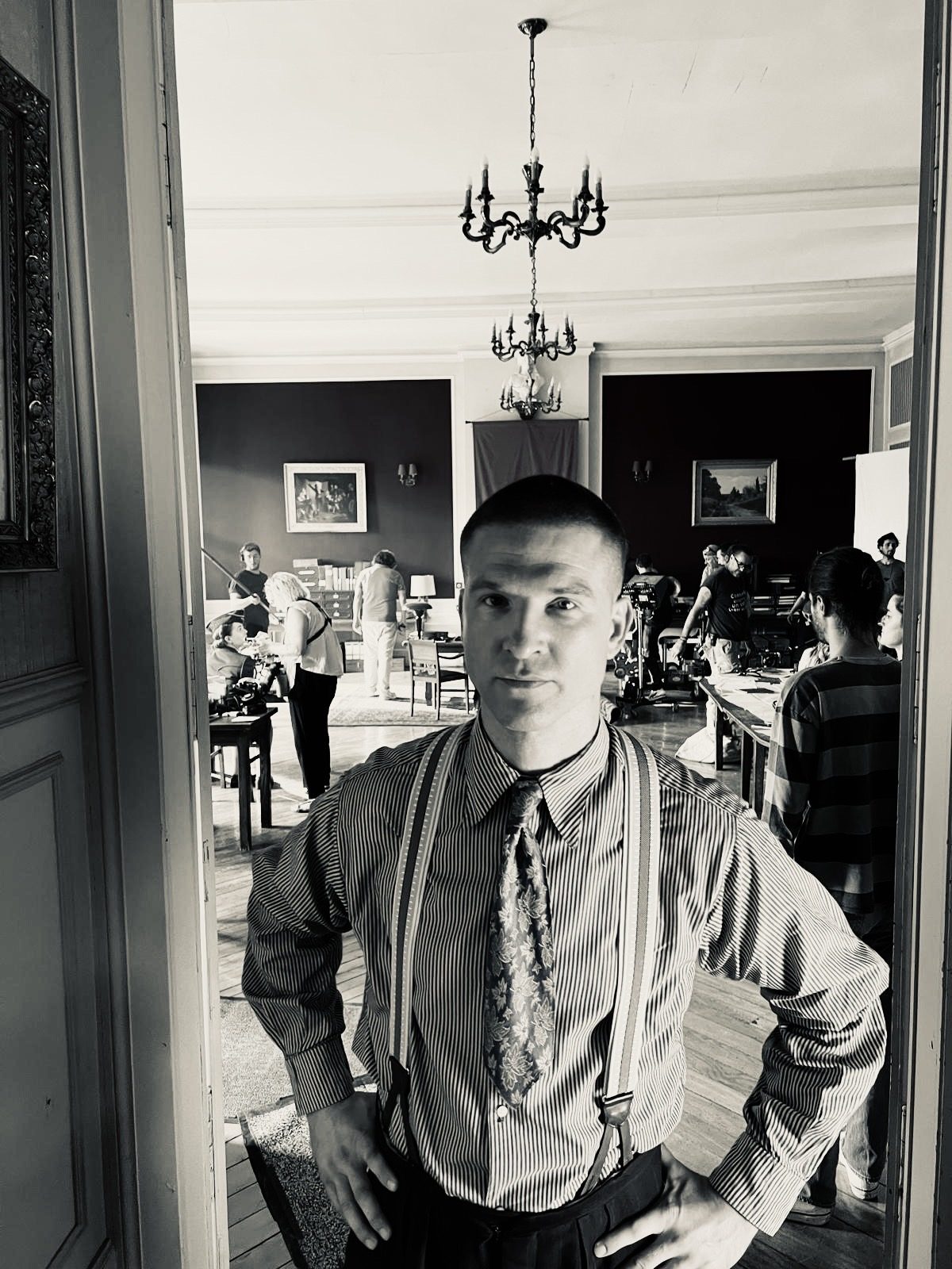 En noir et blanc, bretelles et cravate, dans un intérieur