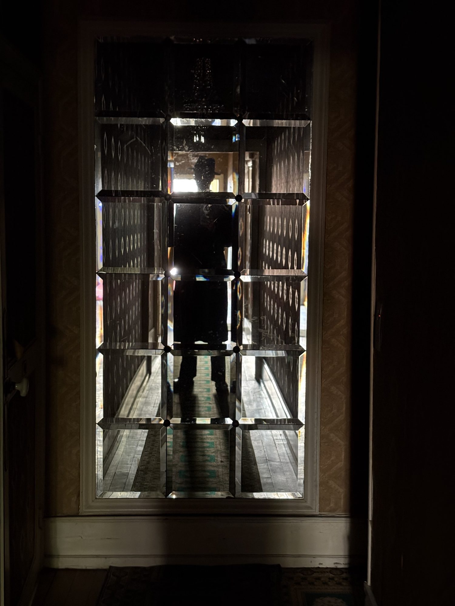 Silhouette au fond d'un couloir sombre, devant une porte vitrée